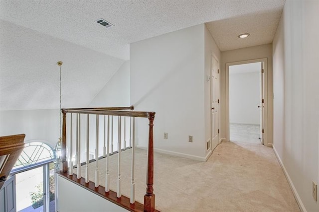 corridor featuring vaulted ceiling, light carpet, and a textured ceiling