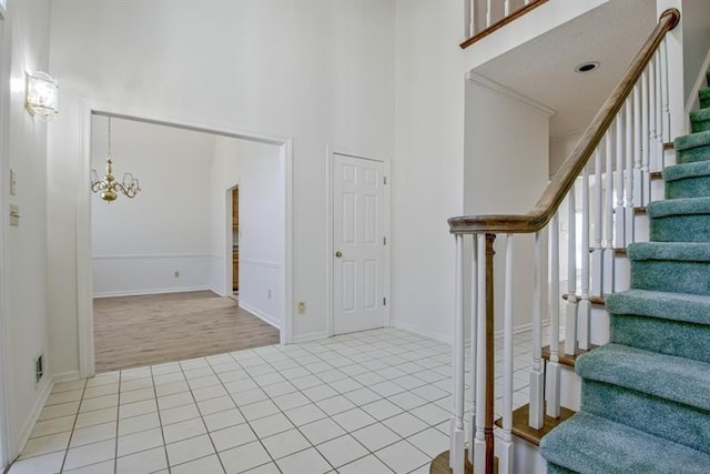 entryway featuring a chandelier, a high ceiling, and light tile patterned flooring