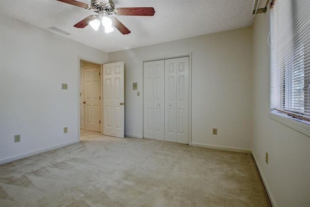 unfurnished bedroom featuring light carpet, ceiling fan, a closet, and a textured ceiling