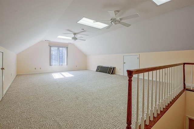 additional living space with ceiling fan, carpet flooring, and lofted ceiling with skylight