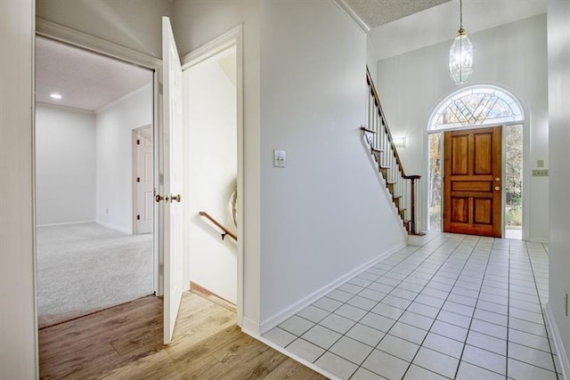 entrance foyer with crown molding, a textured ceiling, a chandelier, and light hardwood / wood-style flooring