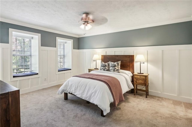 carpeted bedroom featuring ornamental molding, ceiling fan, and a textured ceiling