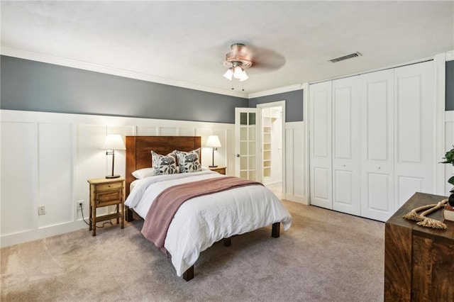 carpeted bedroom with ornamental molding, ceiling fan, and a closet