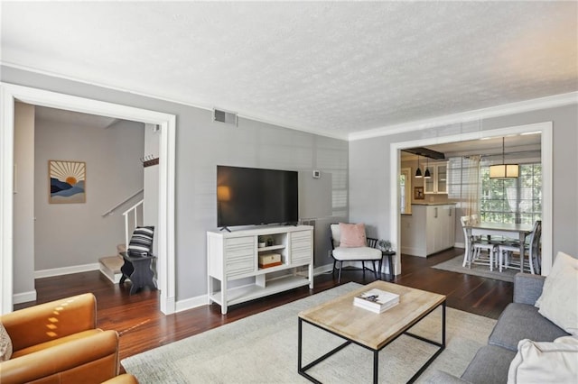 living room with a textured ceiling, dark hardwood / wood-style floors, and crown molding