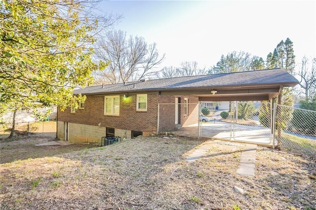 exterior space featuring brick siding, an attached carport, fence, driveway, and a gate