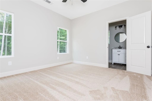 unfurnished bedroom featuring visible vents, baseboards, ensuite bath, and carpet flooring