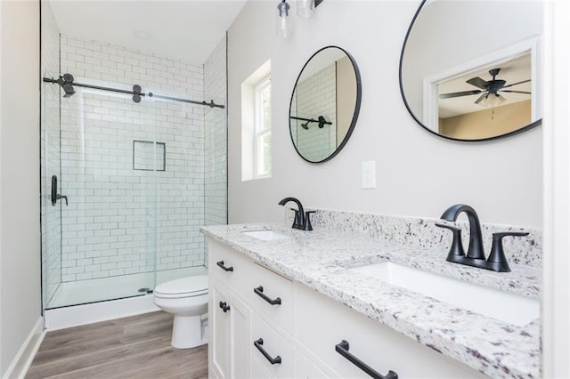 full bathroom with a shower stall, wood finished floors, toilet, and a sink