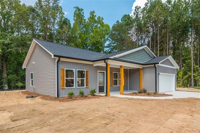 view of front of home featuring covered porch, concrete driveway, an attached garage, and a shingled roof