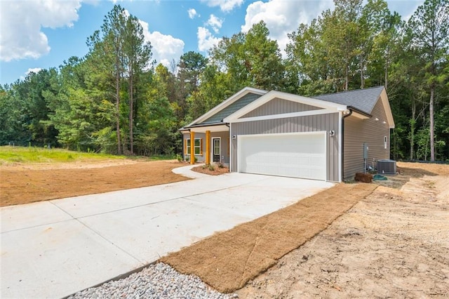 view of front facade featuring central AC, an attached garage, and driveway