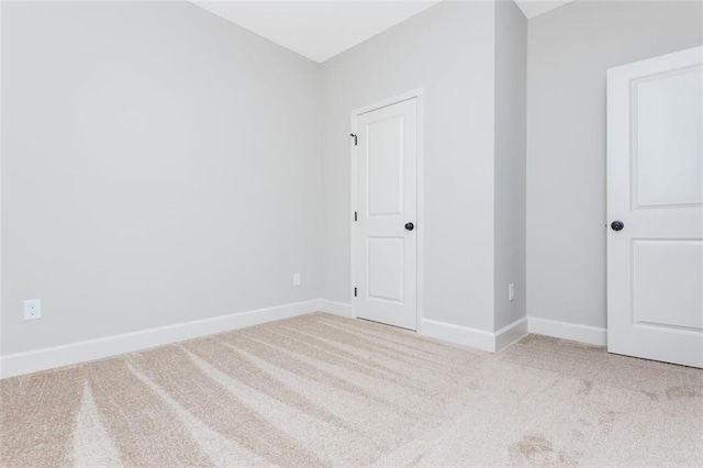 unfurnished room with light carpet and baseboards