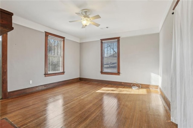 spare room featuring ceiling fan, hardwood / wood-style floors, and a wealth of natural light