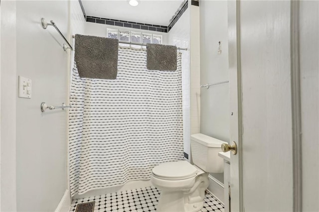 bathroom featuring tile patterned flooring, walk in shower, and toilet