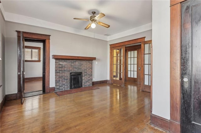 unfurnished living room with ceiling fan, wood-type flooring, and a brick fireplace