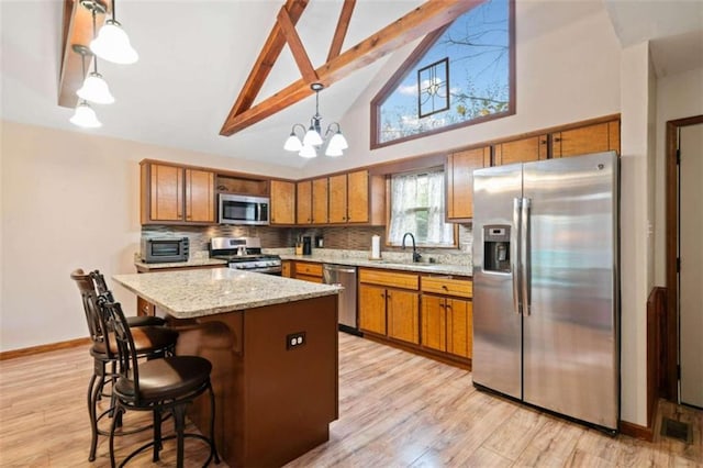 kitchen with a center island, hanging light fixtures, an inviting chandelier, appliances with stainless steel finishes, and light wood-type flooring