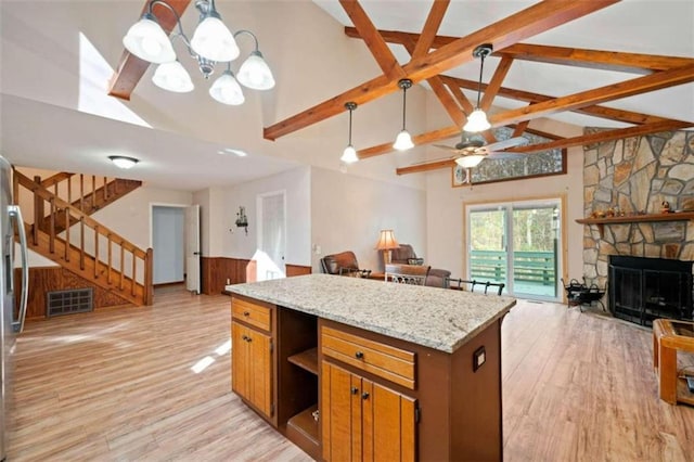 kitchen featuring a center island, ceiling fan with notable chandelier, a fireplace, decorative light fixtures, and light hardwood / wood-style floors