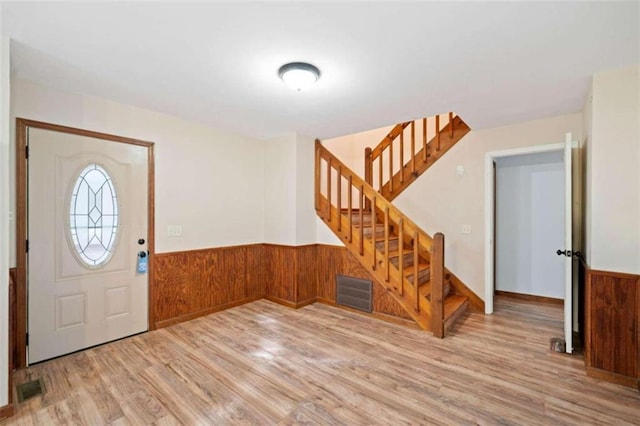 foyer entrance featuring light hardwood / wood-style flooring and wood walls