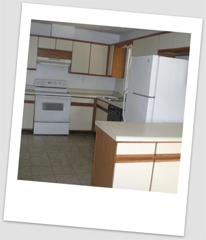 kitchen featuring tile patterned flooring, under cabinet range hood, white appliances, a sink, and light countertops