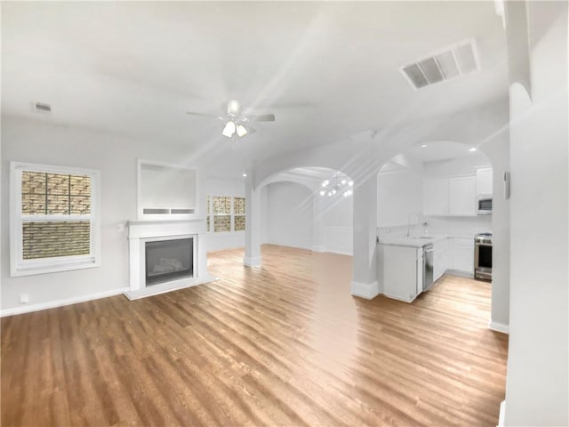 unfurnished living room featuring sink, ceiling fan, and light hardwood / wood-style flooring