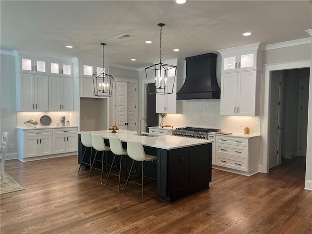 kitchen featuring light hardwood / wood-style floors, exhaust hood, appliances with stainless steel finishes, and a kitchen island with sink