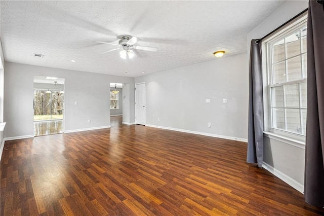 spare room with a textured ceiling, dark hardwood / wood-style floors, plenty of natural light, and ceiling fan