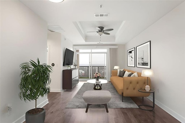 living area with hardwood / wood-style floors, a raised ceiling, and ceiling fan