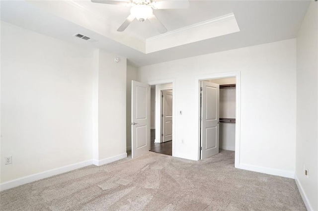 unfurnished bedroom with a raised ceiling, carpet, and ceiling fan