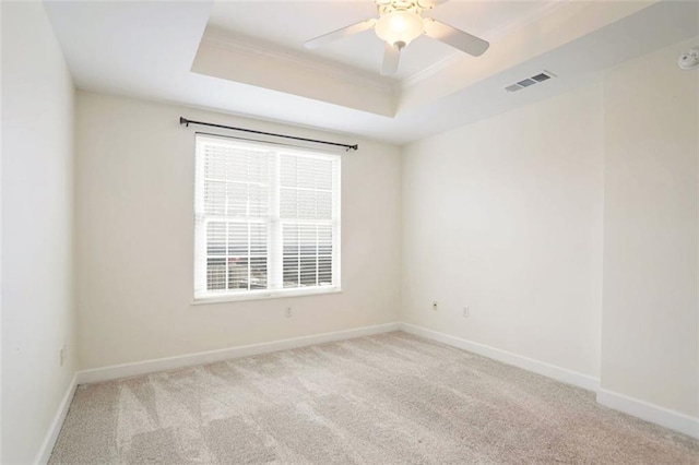 spare room with a raised ceiling, crown molding, light colored carpet, and ceiling fan