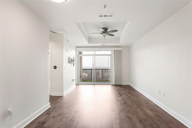 spare room with ceiling fan, dark hardwood / wood-style flooring, and a tray ceiling