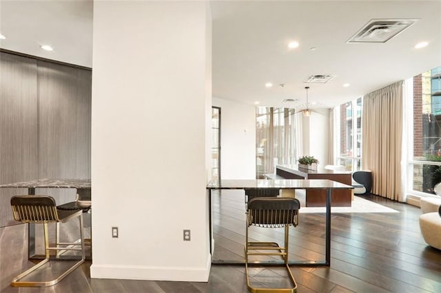 interior space with expansive windows, dark hardwood / wood-style floors, a breakfast bar, and decorative light fixtures