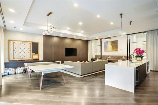 living room with dark wood-type flooring, a tray ceiling, and sink