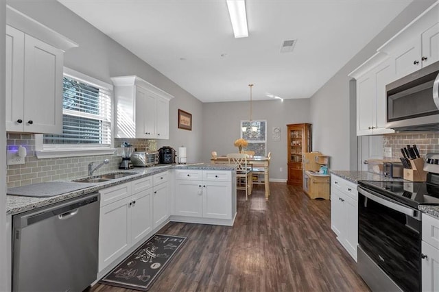 kitchen featuring kitchen peninsula, appliances with stainless steel finishes, decorative backsplash, and white cabinetry