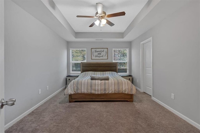 unfurnished bedroom with a raised ceiling, ceiling fan, and carpet flooring