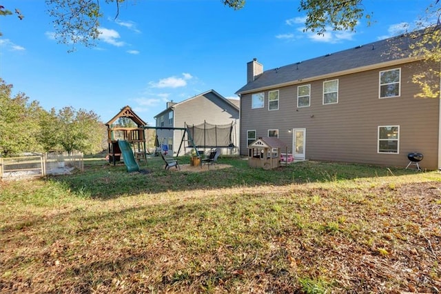 rear view of house with a playground, a yard, and a trampoline