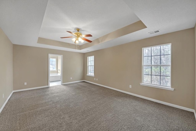 empty room featuring carpet, ceiling fan, and a tray ceiling