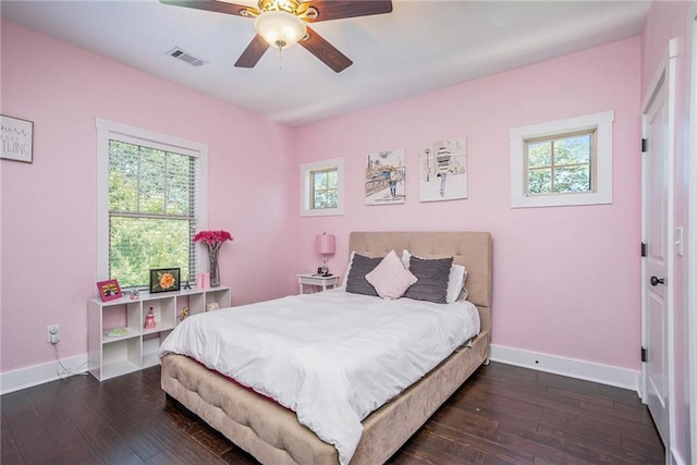 bedroom featuring multiple windows, dark hardwood / wood-style floors, and ceiling fan