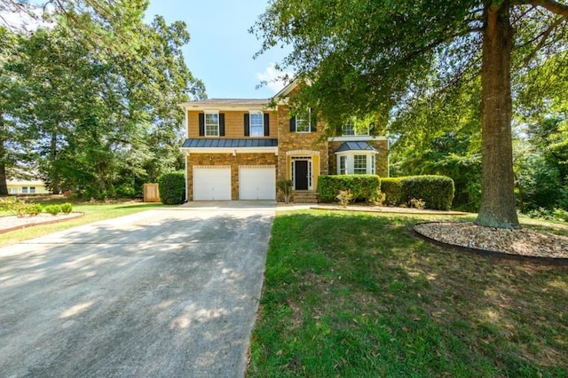 view of front of home with an attached garage, a standing seam roof, metal roof, driveway, and a front lawn