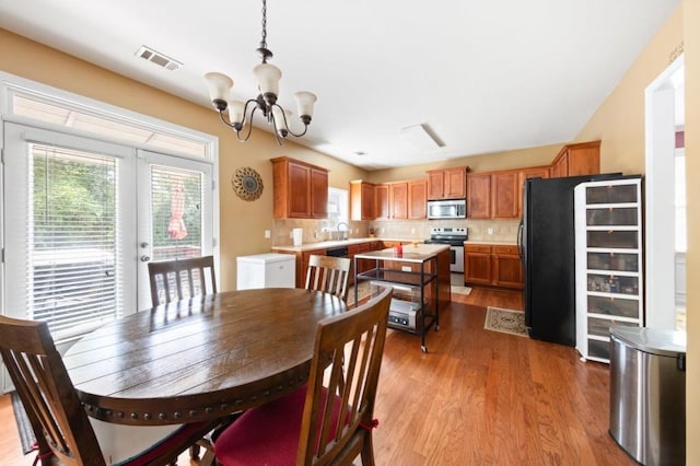 dining space with light wood-type flooring, an inviting chandelier, visible vents, and french doors
