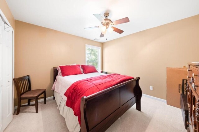 bedroom with a closet, ceiling fan, and light carpet