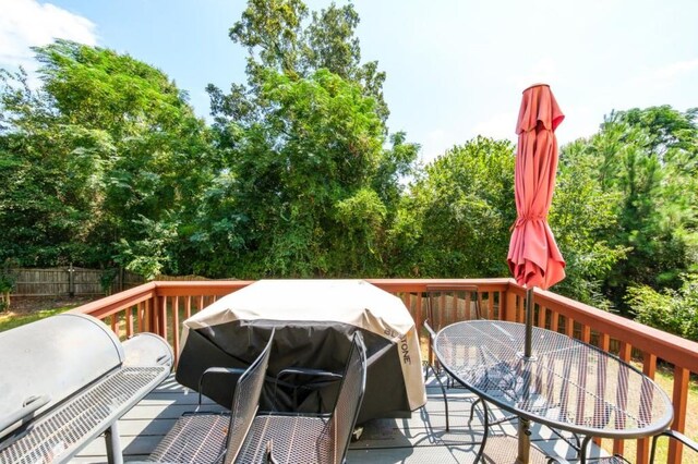 wooden terrace with a grill, fence, and outdoor dining space