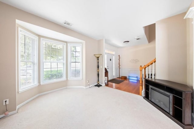 interior space with carpet floors, visible vents, baseboards, and stairs
