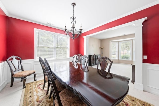 dining space featuring a chandelier, a wainscoted wall, visible vents, ornamental molding, and decorative columns
