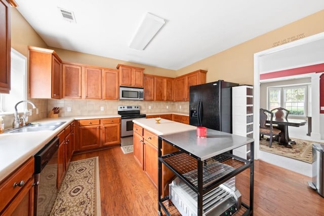 kitchen with sink, stainless steel appliances, decorative backsplash, and wood-type flooring