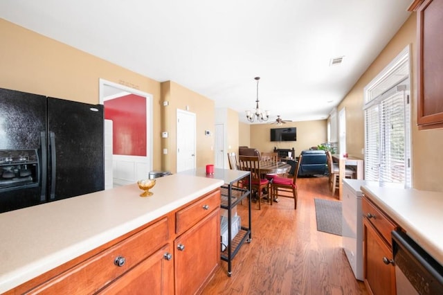 kitchen featuring black fridge, light wood-type flooring, stainless steel dishwasher, and a chandelier