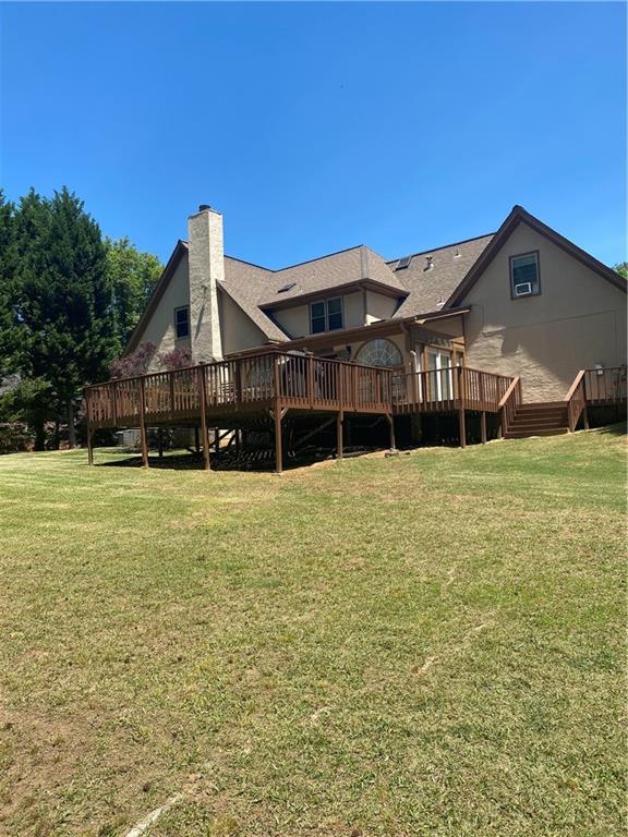 1173 Jimson Cir SE, Conyers, GA 30013 - rear view of property featuring a chimney, a wooden deck, and a lawn