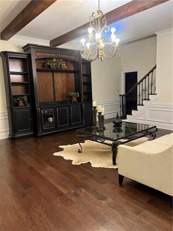 1173 Jimson Cir SE, Conyers, GA 30013 - dining room featuring beamed ceiling, a chandelier, wood-type flooring, a decorative wall, and stairway