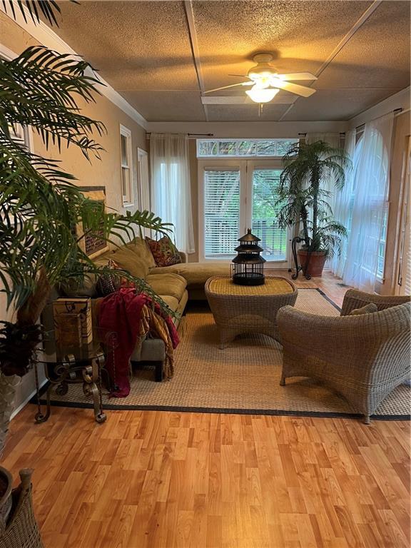1173 Jimson Cir SE, Conyers, GA 30013 - living room featuring ceiling fan, light wood-type flooring, a textured ceiling, and ornamental molding