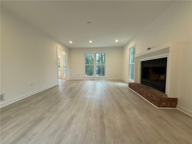 unfurnished living room featuring a fireplace and light hardwood / wood-style floors