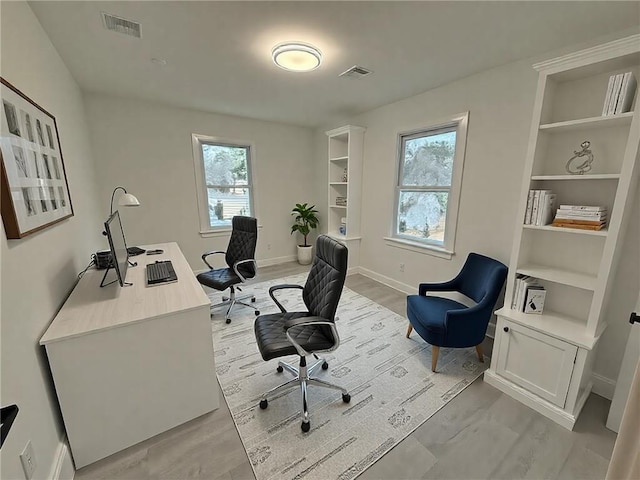 office space with built in features and light wood-type flooring