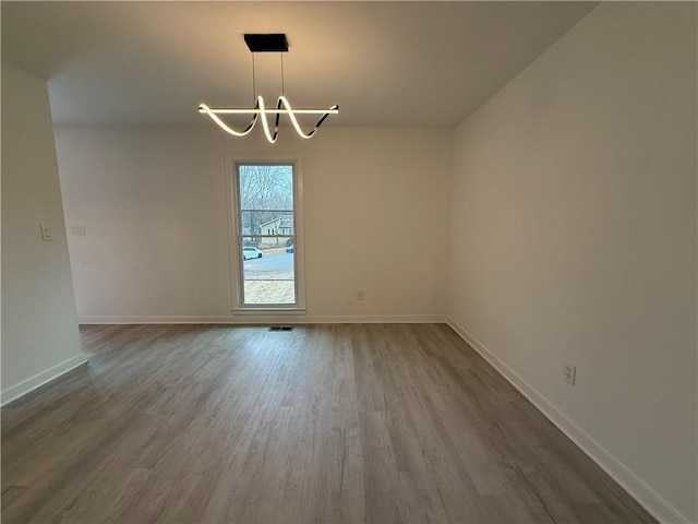 spare room featuring hardwood / wood-style floors and a notable chandelier