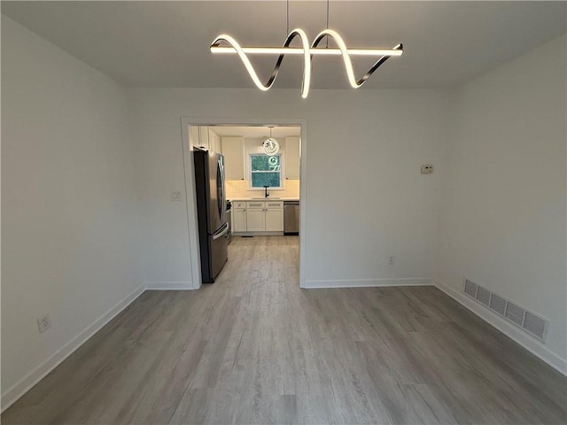 unfurnished dining area featuring sink and light hardwood / wood-style flooring